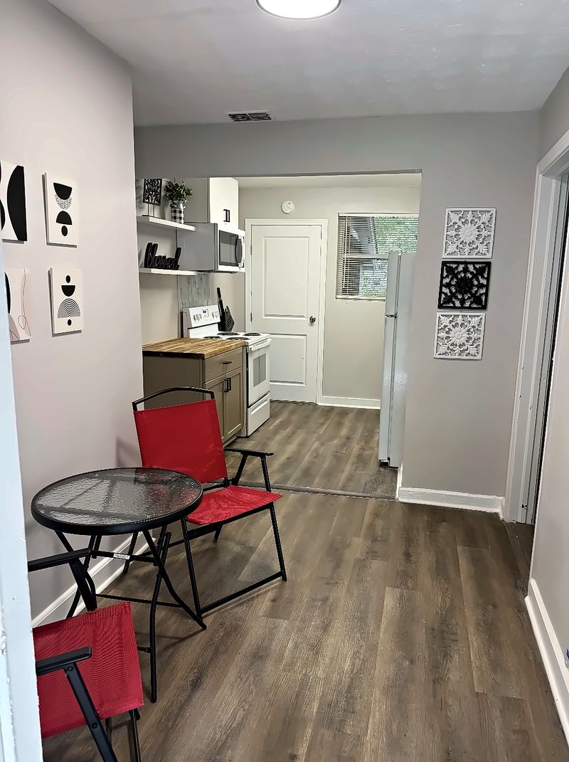 Dining nook with a small table and chairs, looking into the kitchen