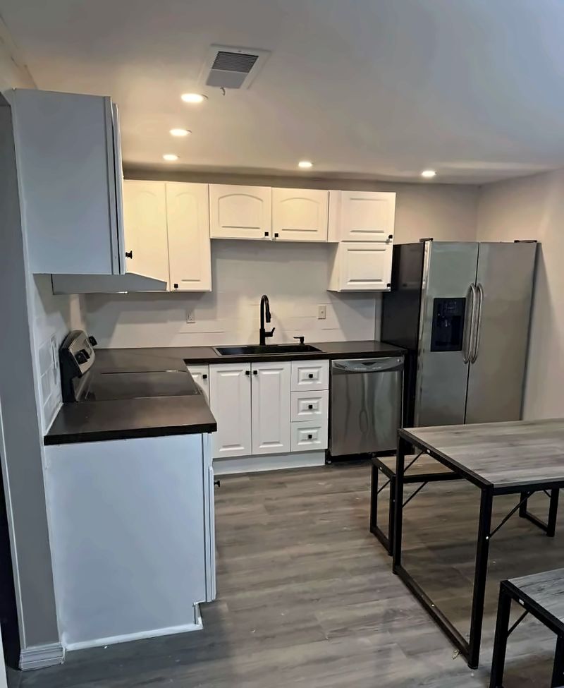 Kitchen with white cabinets, a stainless refrigerator and dishwasher, and a dining table