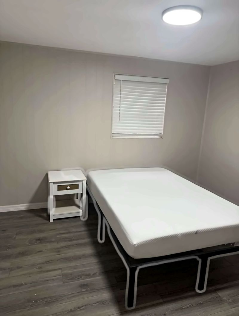 Bedroom with a bed, a nightstand, and a window