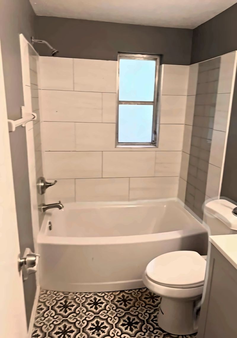Bathroom with a tub and a patterned tile floor