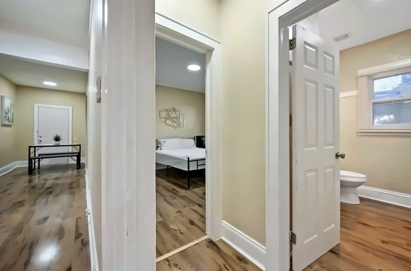 Hallway view into a bedroom, the bathroom, and the dining table area