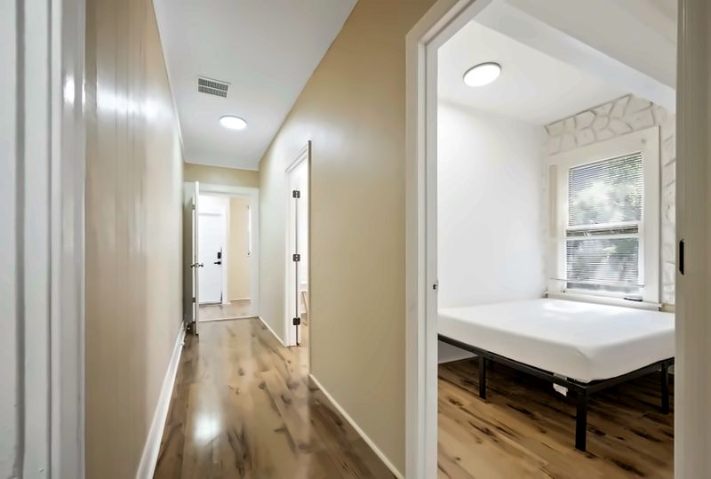 Hallway, with a bedroom with a stone accent wall on the right