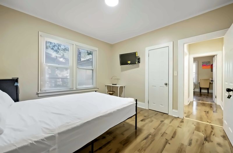 Bedroom with a bed, wall-mounted TV, closet, and wood-look floors