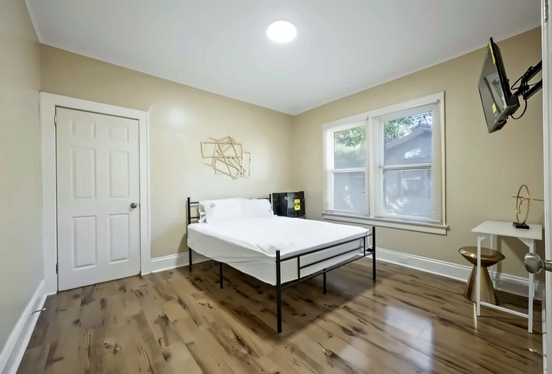 Bedroom with gold wall art, a bed, mini fridge, swivel-mount TV, and a side table