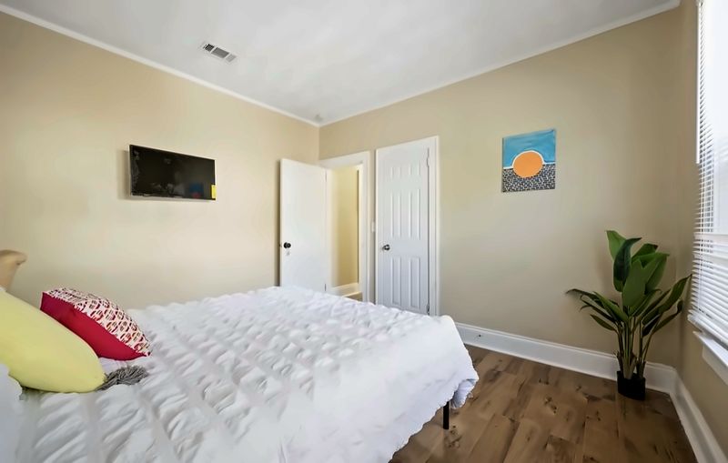 Bedroom with a bed, wall-mounted TV, a plant, and wall art